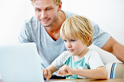 Buy stock photo A young father helping his little boy on his laptop