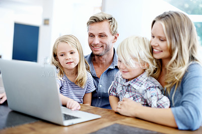 Buy stock photo Cute young family looking at a laptop together while at home