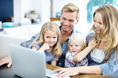 Buy stock photo Cute young family looking at a laptop together while at home