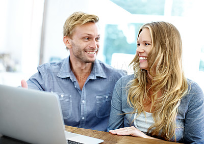 Buy stock photo Happy young couple looking at a laptop together at home