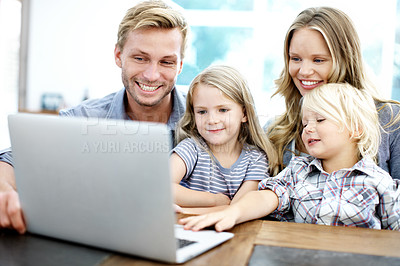 Buy stock photo Cute young family looking at a laptop together while at home