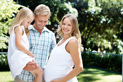 Buy stock photo Smiling young couple standing in a garden with their young daughter