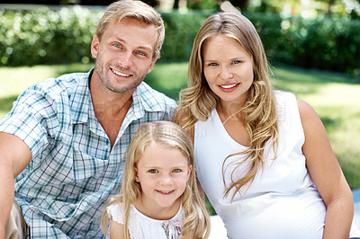 Buy stock photo Smiling young couple sitting in a garden with their young daughter