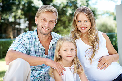 Buy stock photo Smiling young couple sitting in a garden with their young daughter