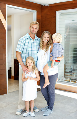 Buy stock photo Young family standing in the doorway of the home with welcoming smiles