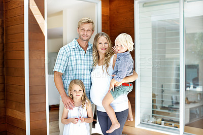 Buy stock photo Young family standing in the doorway of their home with welcoming smiles