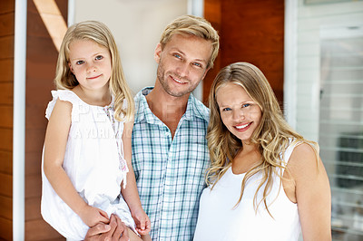 Buy stock photo Young family standing in the doorway of their home with welcoming smiles