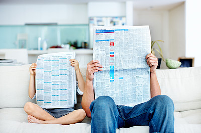 Buy stock photo Little boy and his father reading newspapers that cover their faces on the sofa at home