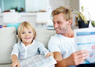 Buy stock photo Cute little boy pretending to read a newspaper like his father while on the sofa at home