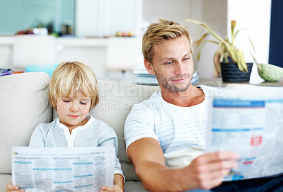 Buy stock photo Cute little boy pretending to read a newspaper like his father while on the sofa at home