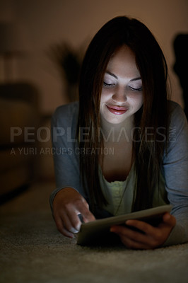 Buy stock photo A teenage girl lying on the floor holding a digital tablet