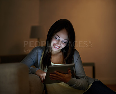 Buy stock photo A gorgeous teenage girl typing on her digital tablet while leaning on a couch
