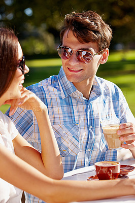 Buy stock photo Handsome man enjoying an afternoon latte with his girlfriend at an outdoor cafe