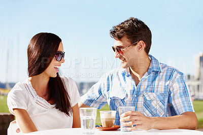 Buy stock photo Loving young couple enjoying coffee at an outdoor cafe on a sunny day