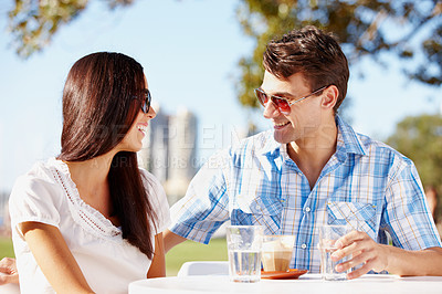 Buy stock photo Loving young couple enjoying coffee at an outdoor cafe on a sunny day