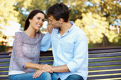 Buy stock photo Beautiful young couple gazing into each other's eyes in the park on a sunny afternoon