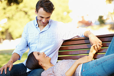 Buy stock photo Loving couple talking happily on a park bench on a sunny afternoon