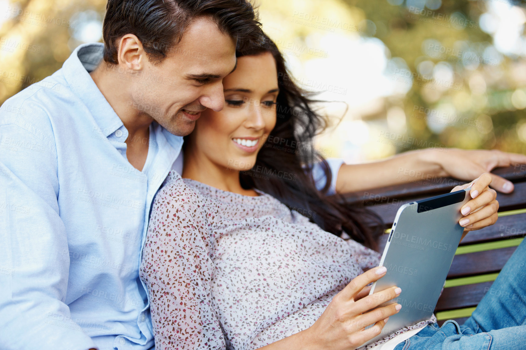 Buy stock photo Smile, search and tablet with couple on park bench for social media post, date and online update. Happiness, summer vacation and connection with man and woman with tech outdoor for care and love