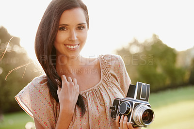 Buy stock photo Beautiful young woman posing outdoors with a vintage camera and gentle sunlight behind her