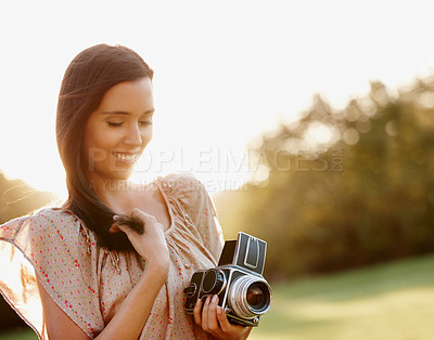 Buy stock photo Beautiful young woman posing outdoors with a vintage camera and gentle sunlight behind her - copyspace