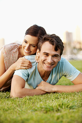 Buy stock photo Happy young couple lying on the grass in a park