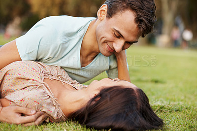 Buy stock photo Closeup of a loving young couple embracing while lying on some grass in a park - copysace