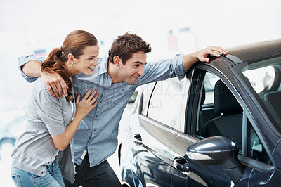 Buy stock photo Car, hug and shopping with couple in dealership together for decision or purchase. Buying, choice and retail sale with happy people on showroom floor for consumerism, insurance or vehicle finance