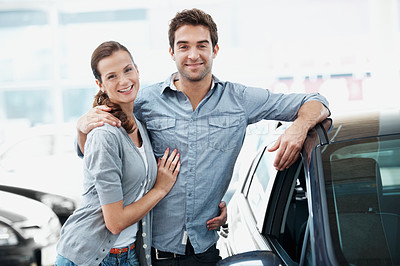 Buy stock photo Portrait, couple and happy at dealership with car, inspection and test drive for transport selection. Smile, people and embrace in showroom with vehicle, finance approval and auto purchase decision