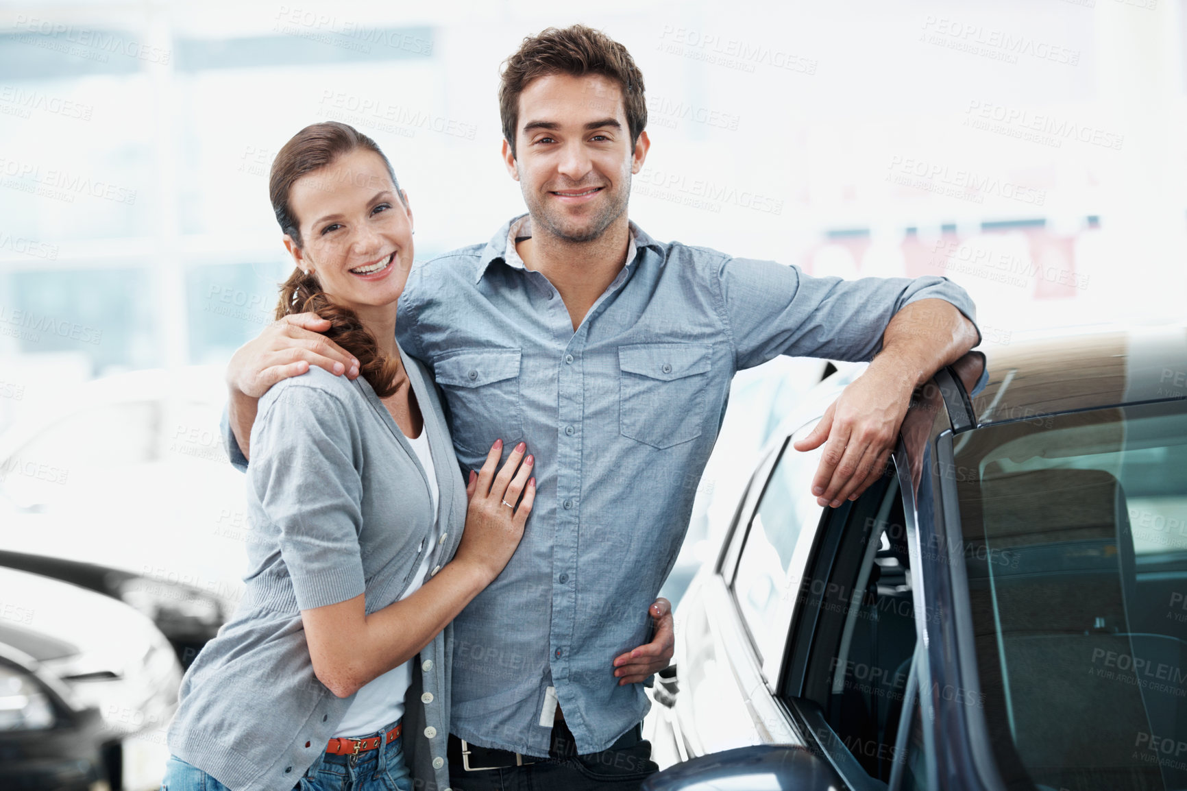 Buy stock photo Portrait, couple and happy at dealership with car, inspection and test drive for transport selection. Smile, people and embrace in showroom with vehicle, finance approval and auto purchase decision