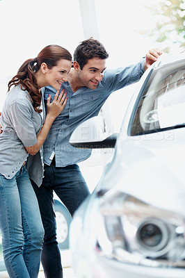 Buy stock photo Hug, couple and shopping at car dealership, check and decision for automobile with support. Showroom, happy man and woman with vehicle inspection for purchase, embrace and customers with transport