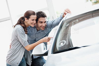 Buy stock photo Car, pointing and shopping with couple in dealership together for decision or purchase. Choice, retail and sale with happy people on showroom floor for consumerism, insurance or vehicle finance