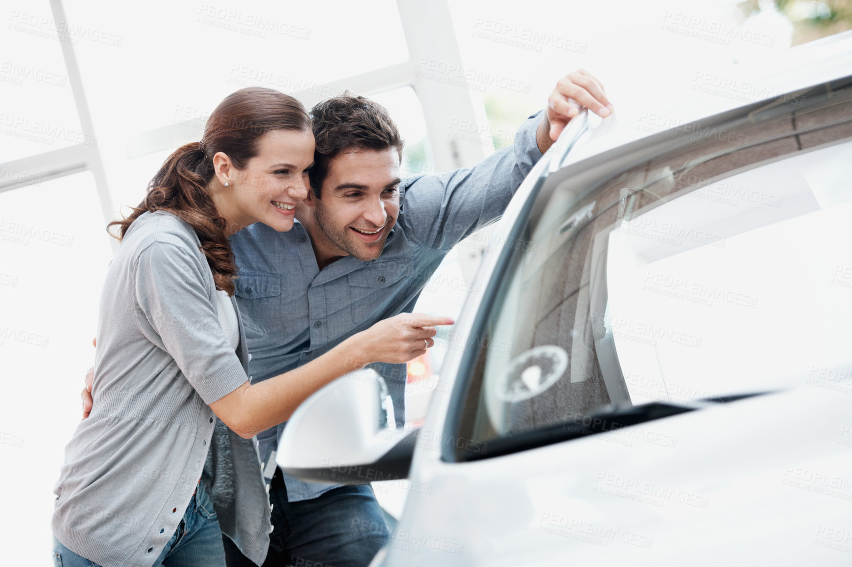 Buy stock photo Car, pointing and shopping with couple in dealership together for decision or purchase. Choice, retail and sale with happy people on showroom floor for consumerism, insurance or vehicle finance