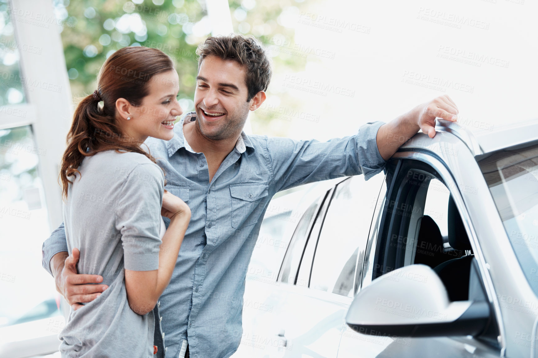 Buy stock photo Car, hug and shopping with happy couple in dealership together for decision or purchase. Buying, laughing and sale with people embracing in showroom for consumerism, insurance or vehicle finance