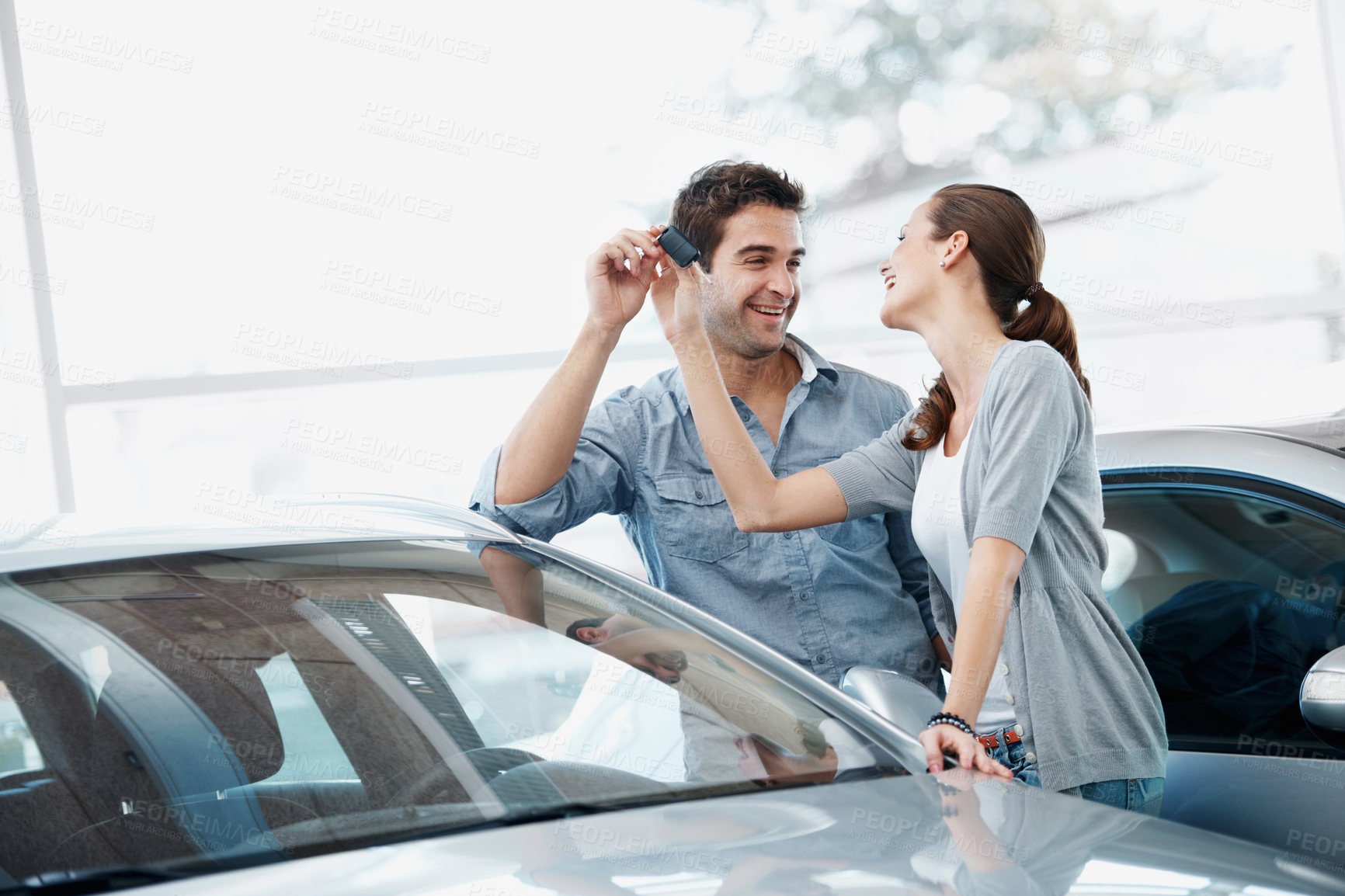 Buy stock photo Couple, smile and purchase in car dealership with keys, transport investment and motor insurance. Married people, shopping together and customer buy new vehicle in store with discount, promo or sale.