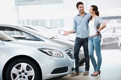 Buy stock photo Happy, couple and browsing in dealership for new car, consider sale promotion and motor insurance. Married people, smile and shopping in store for vehicle, investment decision and retail purchase.