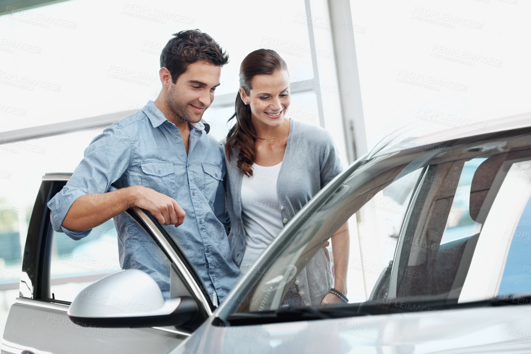 Buy stock photo Happy, couple and inspection at dealership with car, features and transport for test drive. Smile, people or quality control in showroom with vehicle, finance approval and collection of auto purchase