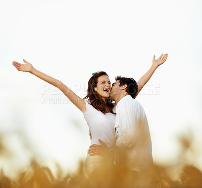 Buy stock photo Happy, kiss and couple with open arms in corn field for love, affection or outdoor romance together. Man, woman or smile with hug, embrace or intimacy for freedom, holiday or weekend in countryside