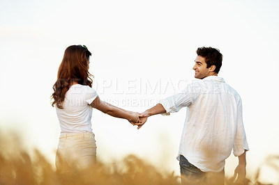 Buy stock photo Couple, holding hands and walking outdoor in meadow, partner and support with care in nature. People, marriage and romantic stroll for healthy relationship, bonding and together with space for love