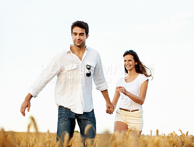 Buy stock photo Walking, holding hands and couple in wheat field for bonding, vacation or romance in countryside. Happy, man and woman in nature for weekend trip together with holiday, anniversary and playful travel