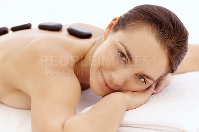 Buy stock photo Beautiful young woman enjoying a hot stone treatment while lying on a spa bed - closeup 