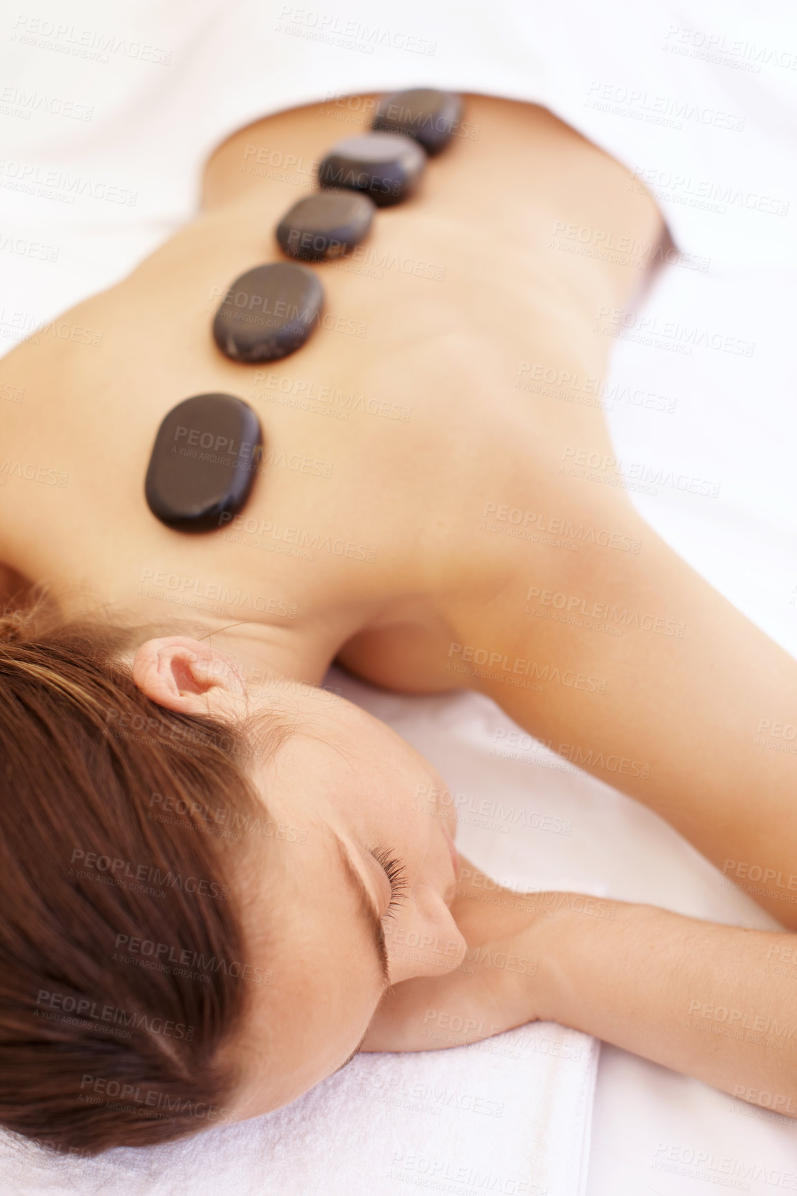 Buy stock photo Woman, spa and hot stone massage for bodycare, wellness and break with self care for stress relief. Female person, luxury and warm rocks on back, treatment and detox with calm or peace at resort