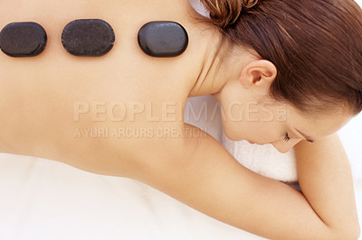 Buy stock photo Attractive young woman enjoying a hot stone treatment while lying on a spa bed 