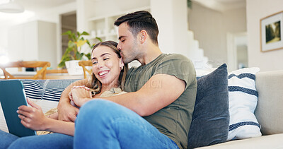 Buy stock photo Kiss, tablet and couple in home with love, booking vacation or planning trip on sofa together. Tech, man and happy woman hug in lounge, holding hands or romantic connection with holiday itinerary