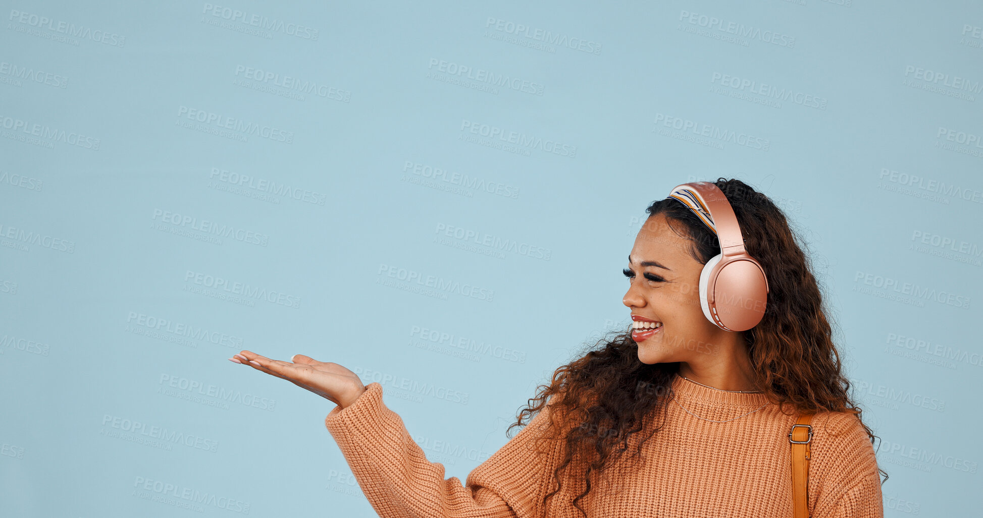 Buy stock photo Studio, promotion and woman with headphones, point and excited for discount offer or recommendation. Blue background, space and happy person with tech for music, advertising and sale announcement