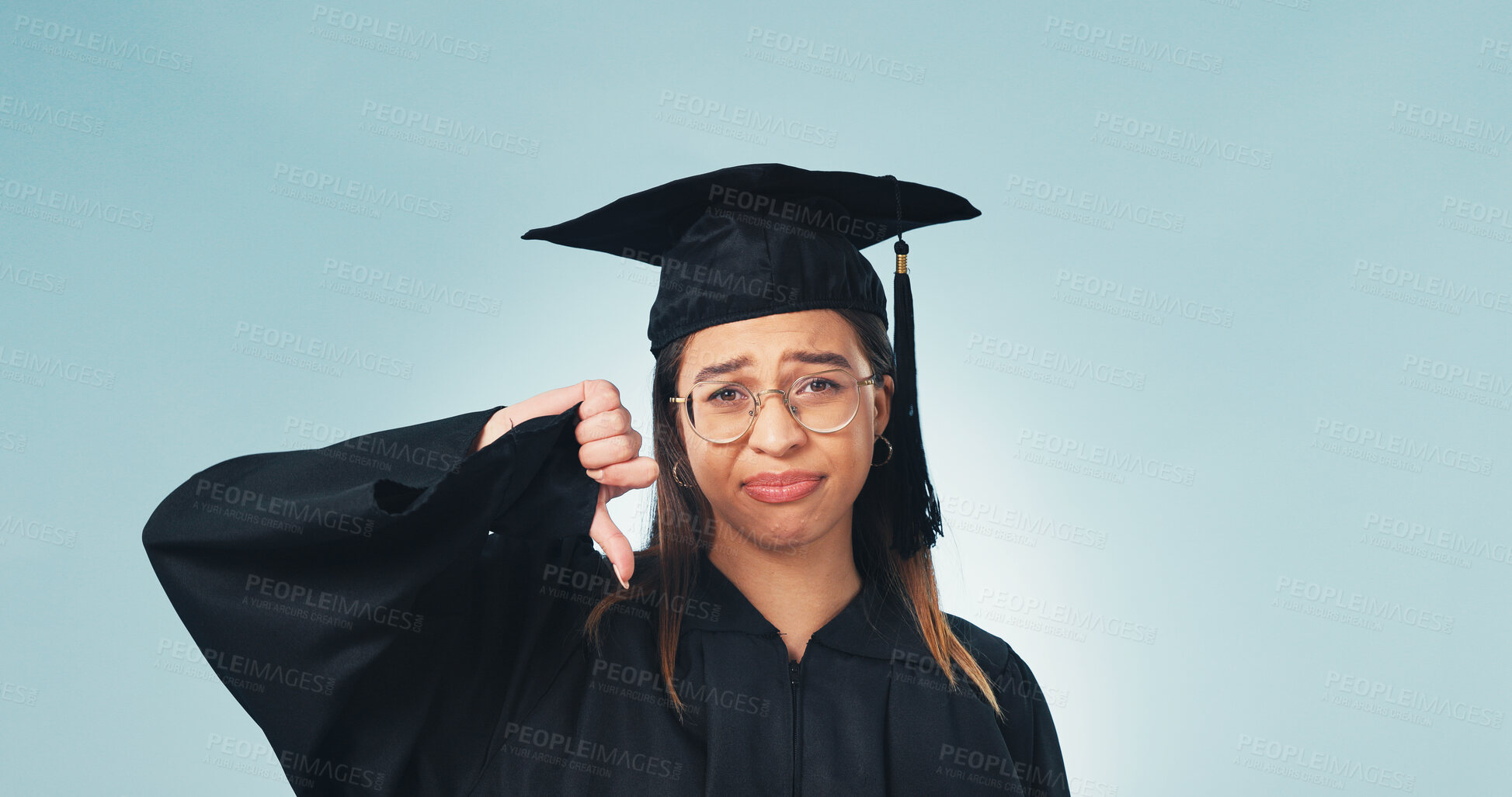 Buy stock photo Thumbs down, portrait and woman in studio for graduation, student loans and worry for future career. Emoji, space and person with bad reaction for university, education or decision on blue background