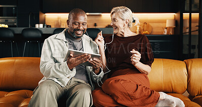Buy stock photo Interracial couple, tablet and smile with earphones for music, app and conversation in home. Mature people, chat and relax for streaming radio, audio subscription and tech for rhythm on social media
