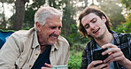 Camping, senior father and son with phone outdoor in nature for bonding, hobby or sharing. App, connection and man with parent in forest for reaction to meme, social media, or text message on mobile