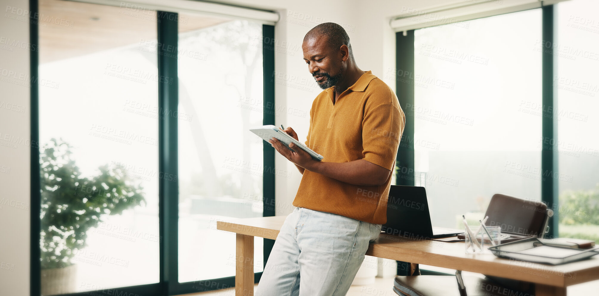 Buy stock photo Creative, black man and reading in home office with tablet, research and sketch for animation. Smile, mature person or freelancer at house with digital, editing cartoon and graphic design for project