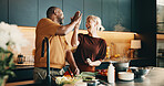 Cooking, high five and laughing with interracial couple in kitchen of home together for meal preparation. Bonding, having fun and success with mature people in apartment for culinary goals or target