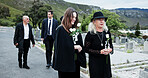 People, sad and flowers in graveyard, support for funeral and mourning for loss. Cemetery, women and family with compassion, grief and burial for death ceremony, memorial service and remembrance